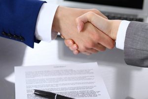 Two men shaking hands over a signed agreement. This guy sure is happy he got fraud bonding services from Access Bonding!